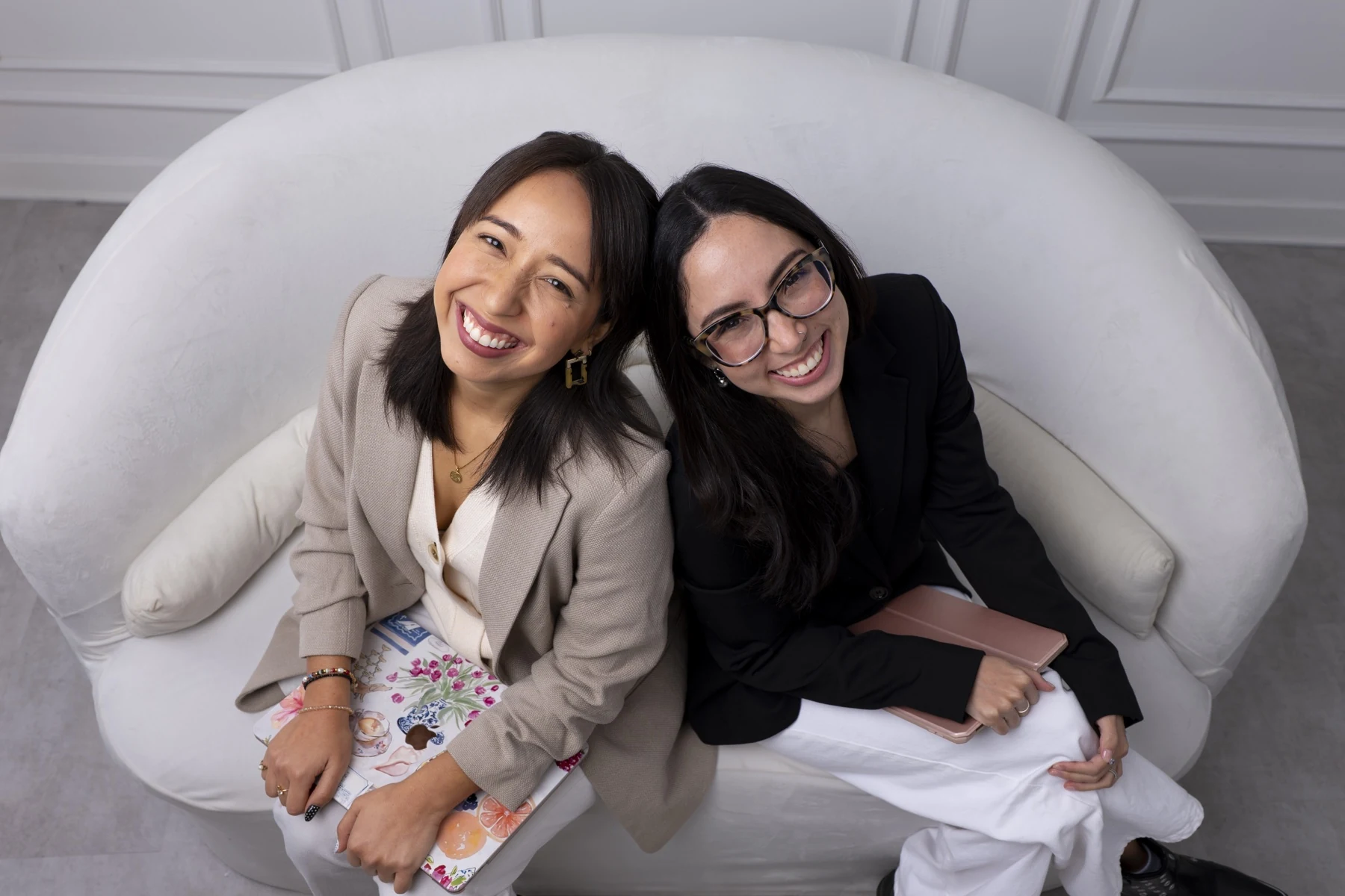 Pierina y Adriana, cofundadoras de Crisalida Studio, sonriendo juntas en un sofá blanco
